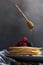 Levitating honey dipper pouring raw honey over homemade crepes on table