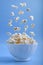 Levitating levitation falling popcorn in a white ceramic bowl and around it on blue background . Side view