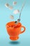 Levitating orange teacup with spoon and sugar cubes