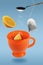Levitating orange teacup with spoon, tea bag and lemon
