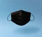 Levitating real black surgical mask with soft shadow on a blue background.