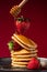Levitating strawberry over a stack of pancakes drizzled with honey