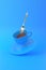 Levitation of Cup of Coffee with a spoon. White mug flying on the air on bright blue background