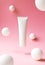 Levitation white plastic tube for cosmetic product on pink background with abstract white spheres, front view. Container for hand