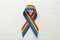 LGBT rainbow ribbon pride symbol. Stop homophobia. White wood background