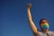 LGBTI equality concept: man with high fist wearing mask with rainbow lgbt flag in coronavirus prevention fighting for his rights