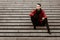 LGBTQ community lifestyle concept. Young homosexual man sits on a stairs. Handsome fashionable gay male model poses in