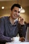 LGBTQ community lifestyle concept. Young homosexual man sits at the table in old-fashioned city cafe. Handsome smiling