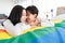 LGBTQ couple lovers, a handsome girl as a man or butch femme girl laying on a bed with the rainbow flag the symbol of LGBT,