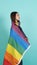 LGBTQ girl and pride flag. Sexy Lesbian girl and LGBT flag standing. blue green background. Asian LGBTQ woman with rainbow scarf o
