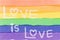 LGBTQ+ sexual diversity concept. Text LOVE is LOVE writing with white shock color on rainbow flag watercolor. Abstract