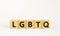 LGBTQ symbol. Concept word acronym `LGBTQ` on wooden cubes. Beautiful white table, white background. LGBTQ concept, copy space