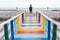 LGBTQ walking alone on colorful rainbow wooden bridge extends into the mangrove sea tourist attractions in Thailand.Lonely travel