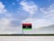 Libya flag with vast meadow and blue sky behind it.