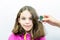 Lice treatment. Girl gets combed for lice with lice comb. Studio portrait.