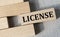 LICENSE - word on a wooden bar on a gray background