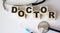 lies a stethoscope, a prick and wooden cubes with the text Doctor