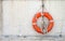 The life buoy with cord is hanged on concrete wall background nearby the beach