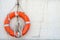 The life buoy with cord is hanged on concrete wall background nearby the beach