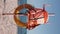 Life Buoy and a Life Jacket Hang on a Post on a Beach in a Seascape.