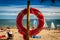 Life buoy on a pole on a sandy beach with blue ocean water