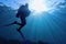 Life-giving sunlight underwater. Sun beams shinning underwater and Scuba diver silhouette in the blue water