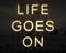 Life Goes On inspiring text in lights against dark landscape background