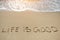 Life in good written on sand beach - positive thinking concept