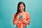Life with a smartphone! Portrait of a beautiful cute young woman wearing an orange shirt holding her phone with both hands reading