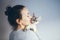 Life style photo of a casual dressed female is holding and petting and kissing cute Devon Rex cat. Kitten enjoys being in girls