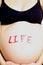 LIFE written on a pregnant belly