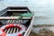 A lifeboat moored near a wooden pier. Inside is a wooden oar and a life preserver. Poor working conditions