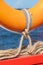 A lifebuoy is attached to a bright orange wooden frame with linen ropes