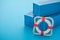 Lifebuoy with blue containers on blue background with copy space. Marine cargo shipment or freight insurance in global shipping