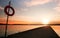 Lifebuoy on the pier in the orange sunrise