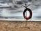 Lifebuoy on a sandy beach. Orange lifebuoy on a pole to rescue people drowning in the sea. Rescue point on the shore