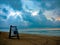 Lifeguard chair on beach with storm clouds