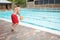 Lifeguard jumping into a swimming pool to rescue drowning senior man