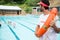 Lifeguard with lifebuoy looking at students playing in the pool