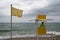 Lifeguard on a lifeguard tower watching on a beach with yellow caution flag