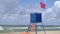 Lifeguard post with a ref flag on it informing about the danger of the wind in the sea