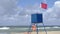 Lifeguard post with a ref flag on it informing about the danger of the wind in the sea