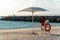 Lifeguard sitting at the beach chair next to umbrella, watching the swimmers in the sea. Important security and rescue.