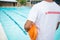 Lifeguard standing with rescue buoy near poolside