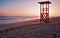 Lifeguard tower, sunrise, footprints on secluded beach with mountains and calm sea, playa de muro, alcudia, mallorca, spain