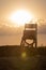 Lifeguard tower at sunset, shot against the sun, with a cloud wi