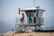 A lifeguard at Ventura Harbor stands watch from a lifeguard tower at a breakwater