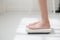 Lifestyle activity with leg of woman stand measuring weight scale for diet with barefoot.