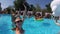 Lifestyle blogger woman taking selfie video with action camera in swimming pool. Travel vlogger films vlog from party at