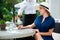 Lifestyle candid portrait of a server pouring sparkling wine to an elegant and classy woman, seated outdoors on countryside restau